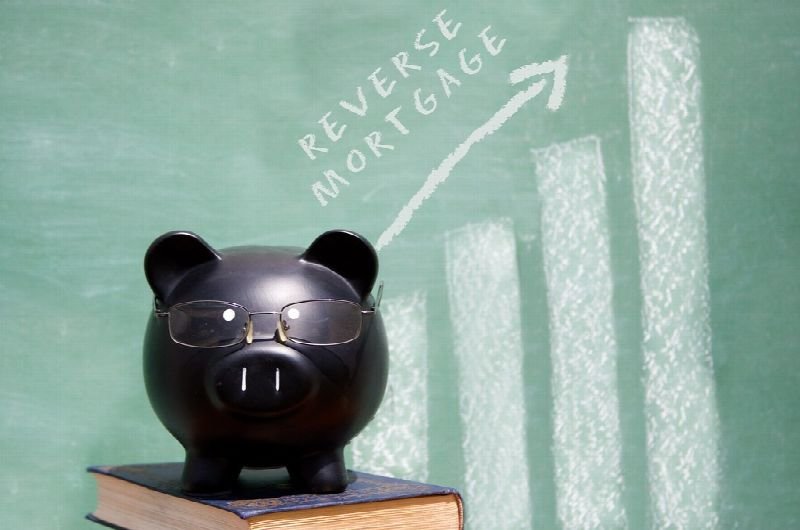 Piggy bank in front of a chalkboard reading reverse mortgage