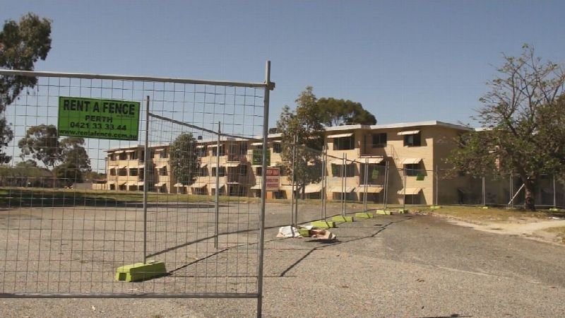 Low-rise apartment complex behind a construction fence