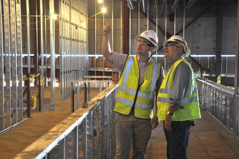 Two contractors in hard hats and safety vests reviewing a renovation site