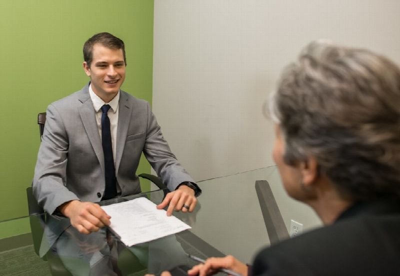 Job candidate in a suit talking with an interviewer across a desk