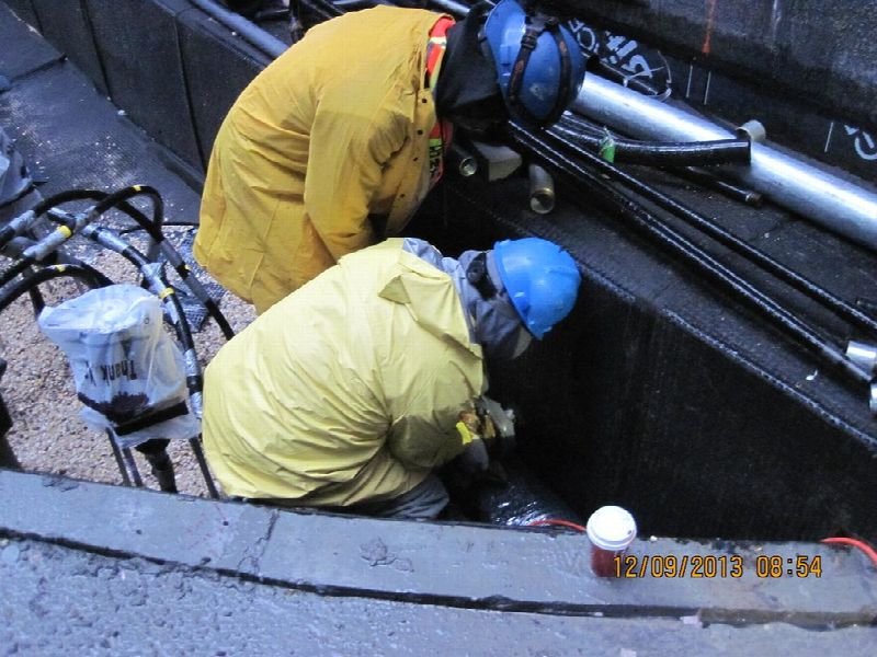 Two electricians in hard hats working on equipment