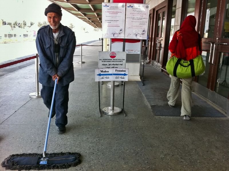 Janitor pushing a dust mop through a building lobby
