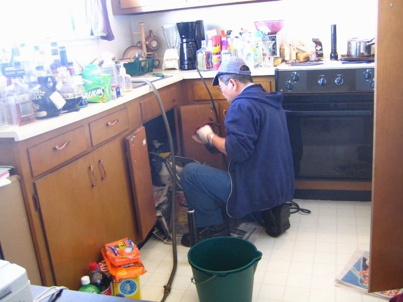 Plumber kneeling to work under a sink cabinet