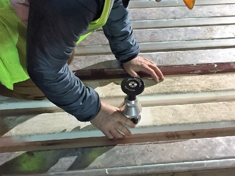 Roofer using a tool on a commercial roof surface