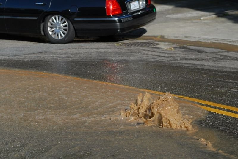 Water from a burst main flowing across a street