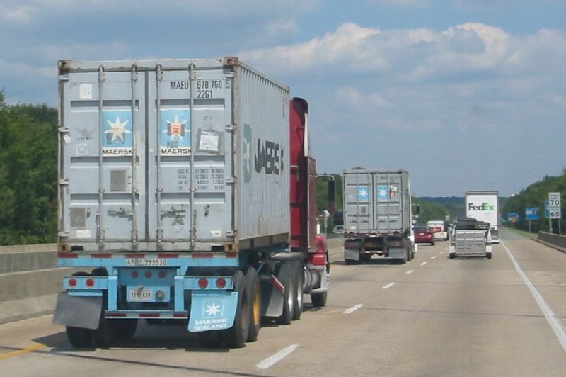 Semi truck hauling a shipping container on a highway