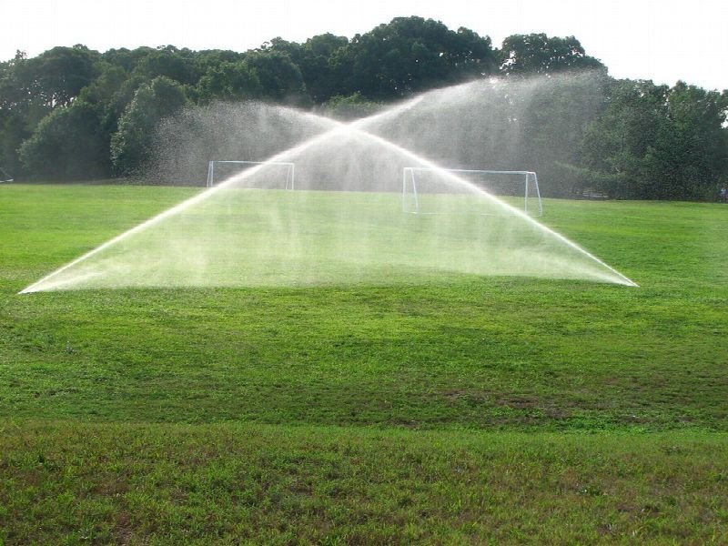 Sprinkler spraying water across a green lawn
