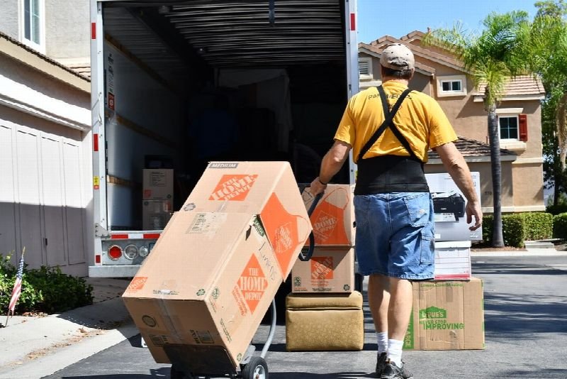 Mover wheeling boxes on a hand truck from a moving truck