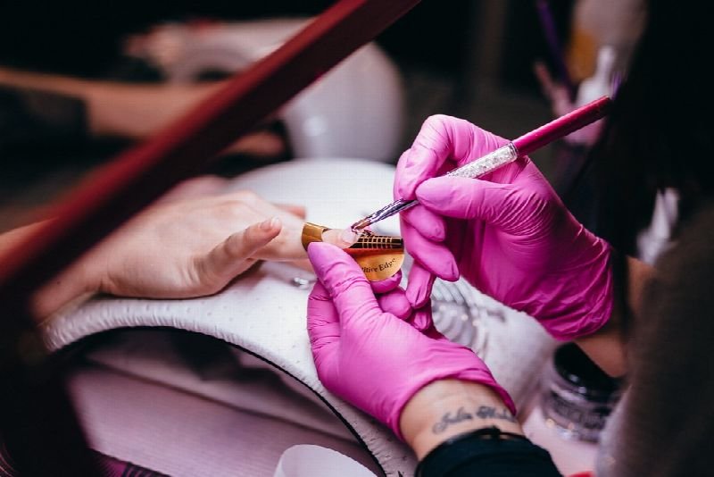 Nail technician in pink gloves doing a manicure