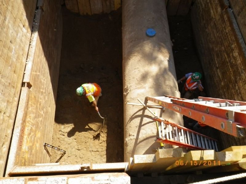 Worker in an excavated trench repairing an underground line