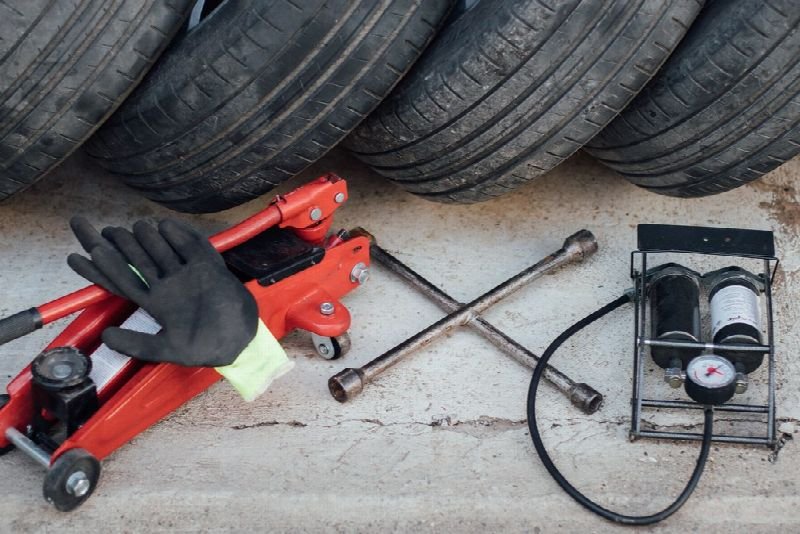 Floor jack, lug wrench and tools in front of stacked tires