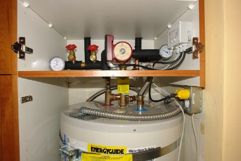 Tank water heater with pipes and valves in a utility closet