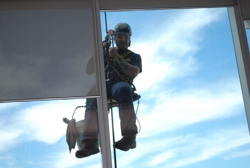 Window washer on ropes cleaning a glass building