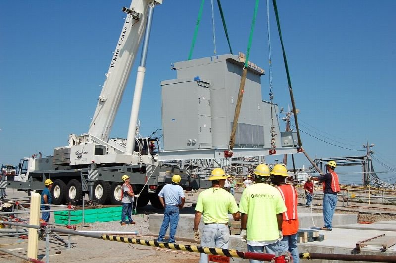 Construction crew in hard hats beside a crane lifting equipment